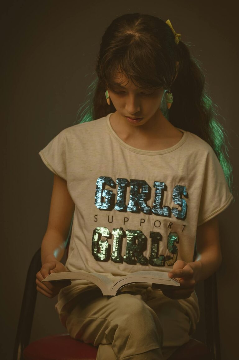 Teenage girl reads a book indoors, illustrating learning and support themes.