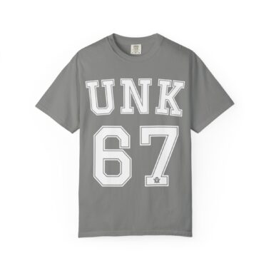 Unk 67 oversized tee laid flat, dark vintage color, large varsity lettering with tiny ghost accent near the number.
